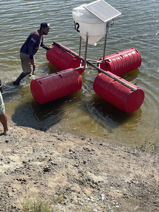 Técnico JBS instalando alimentador automático en piscina camaronera